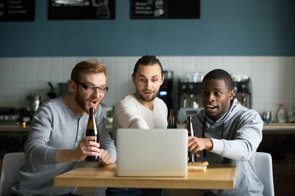 Diverse friends drink beer watching game online in cafe