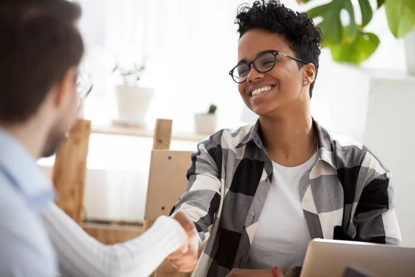 Smiling black female handshake colleague at office meeting