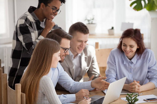 Различные сотрудники мозговой штурм на ноутбуке в офисе вместе
 