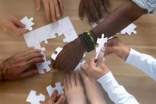 Gros plan mains d'en haut de diverses personnes assembler puzzle — Photo
