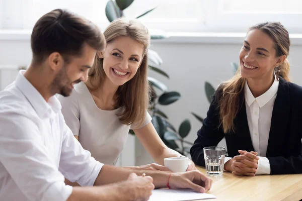 Man signing loan contract sitting at desk with bank workers — Stock Photo, Image