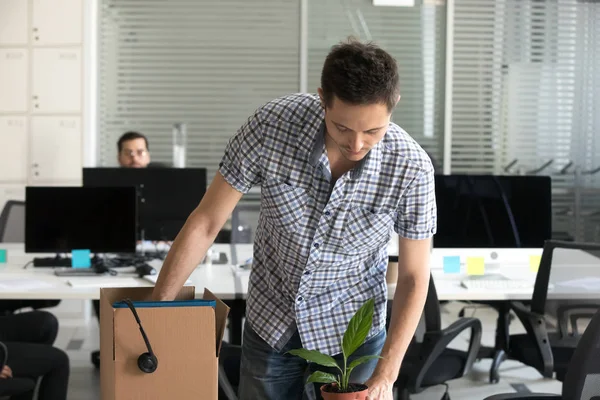 Upset dismissed man packing belongings in cardboard box — Stock Photo, Image