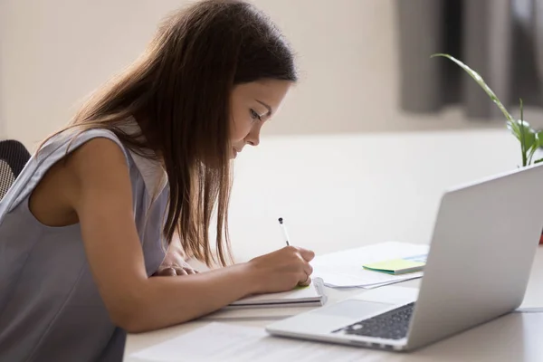 Tânăra fată ține stilou, face note, lucrează cu laptop — Fotografie, imagine de stoc