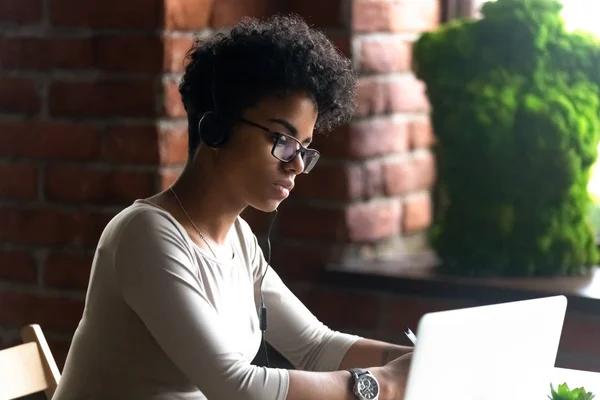 Mujer afroamericana enfocada que usa auriculares con computadora portátil —  Fotos de Stock