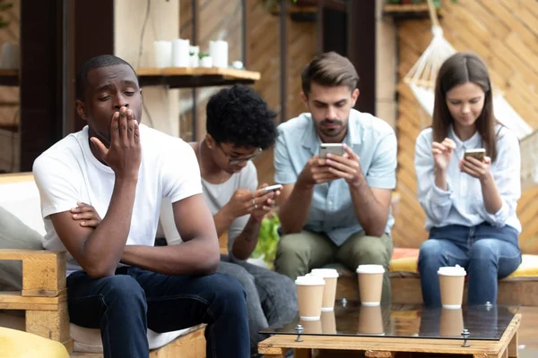 Uttråkad African American man sitter med telefonen beror — Stockfoto