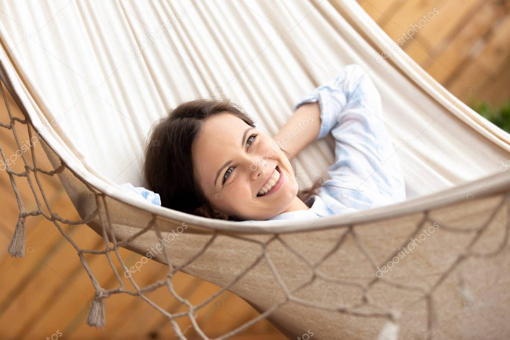 Happy smiling young woman lying in hammock looking in distance