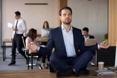 İşadamı masada oturan ve ofiste meditasyon elbiseli
