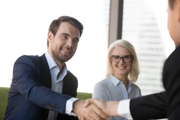 Handsome confident businessman shaking hands with client