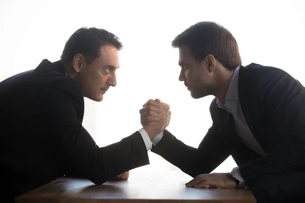 Aged and young businessmen wrestling at office workplace