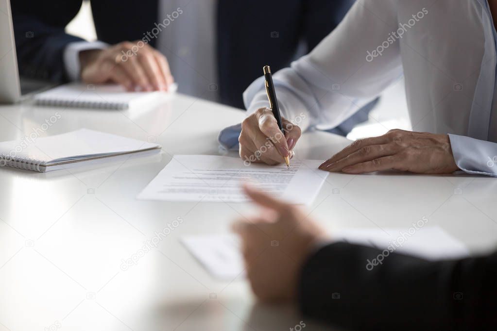 Close up female hands affirming contract with signature during m