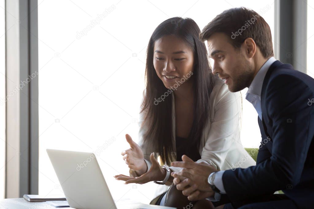 Attractive positive asian female working with caucasian man usin