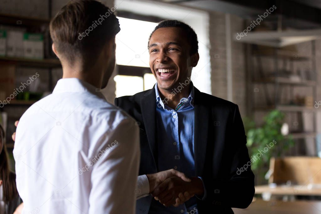 Happy black ceo handshaking rewarding successful worker, employe