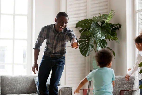 Heureux papa africain riant courir dans le salon attraper les enfants — Photo