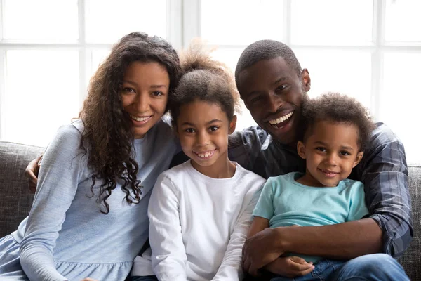 Heureuse famille noire de quatre personnes regardant la caméra à la maison — Photo