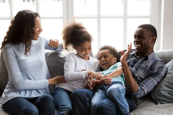 Happy black family laughing playing tickling children at home