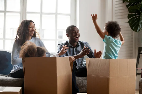 Emocionados niños de raza mixta saltando de la caja jugando con los padres — Foto de Stock