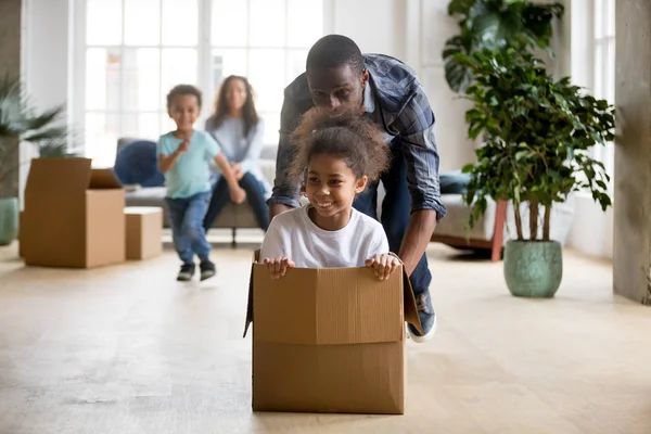 African dad playing with daughter riding in box, moving day