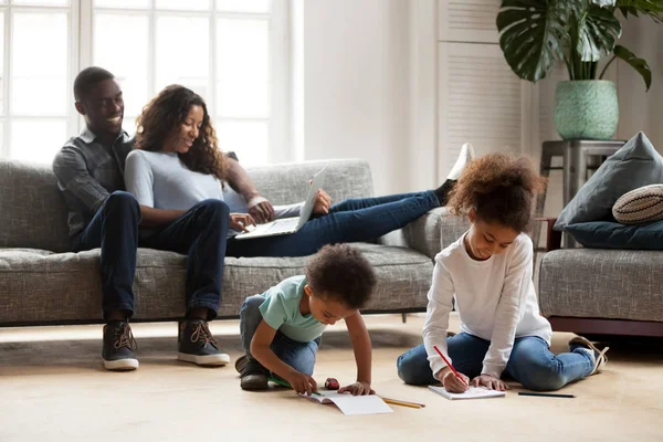 Parents africains se détendre sur le canapé tandis que les enfants jouent ensemble dra — Photo