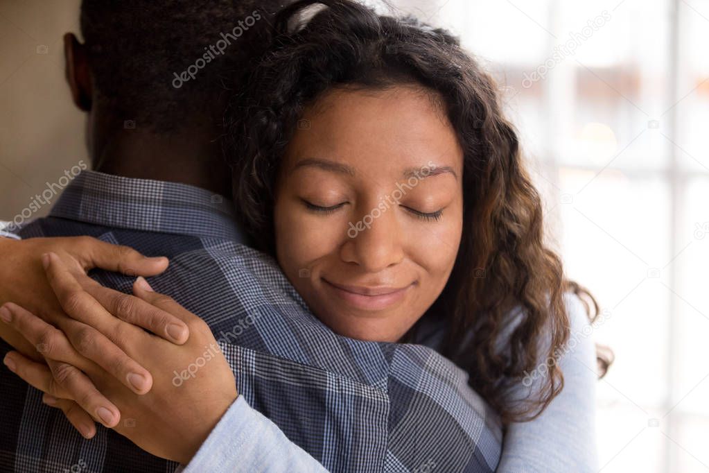 Happy african american wife hugging husband holding tight feelin
