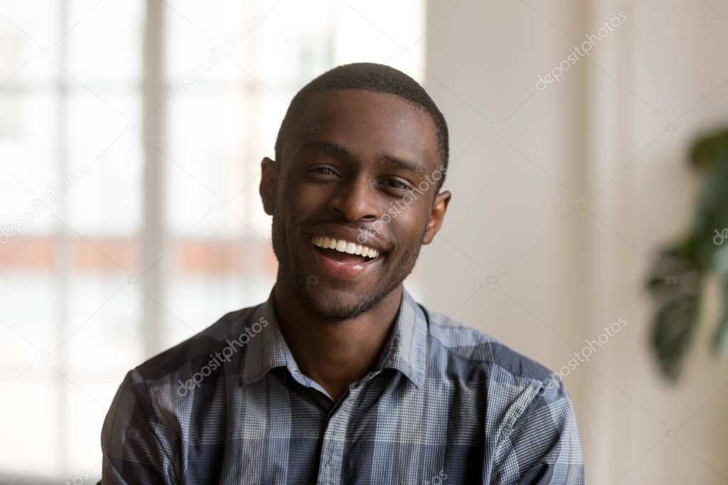 Happy cheerful african millennial man looking at camera at home