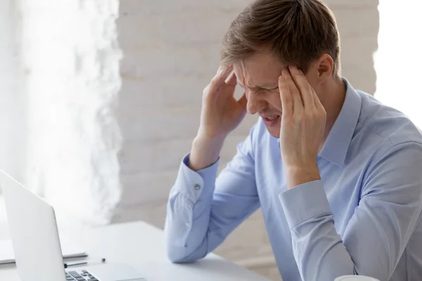 Frustrated businessman feeling pain, massaging temples at workpl — Stock Photo, Image