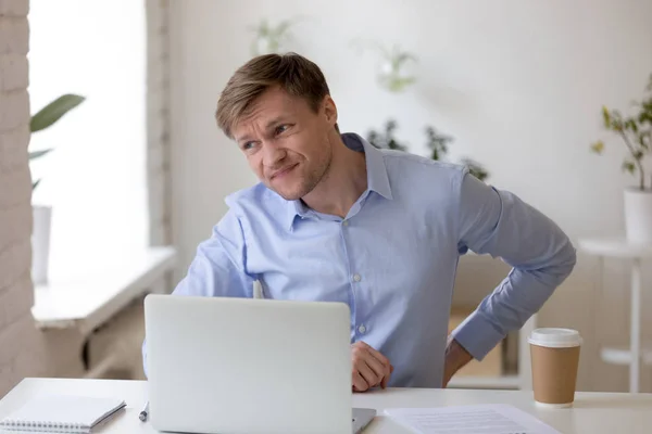 Gefrustreerd zakenman die lijden aan rugpijn op werkplek — Stockfoto