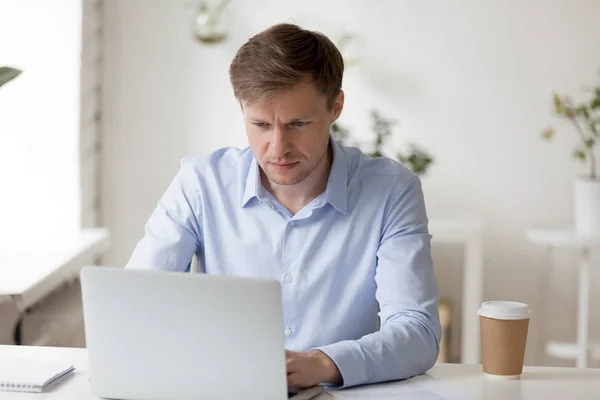 Poważny biznesmen patrząc na ekran laptopa, robi komputer wor — Zdjęcie stockowe