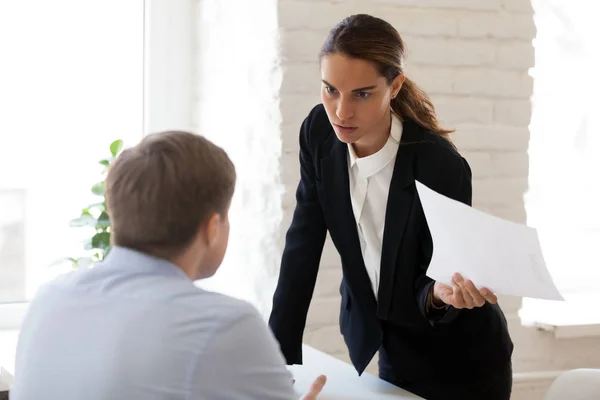 Femme d'affaires sérieuse blâmant employé pour erreur dans le document papier — Photo