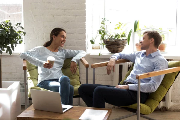 Happy woman laughing with colleague, drinking coffee during brea