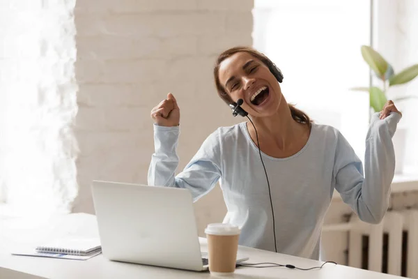 Mulher alegre em fones de ouvido com microfone usando laptop, cantar um — Fotografia de Stock