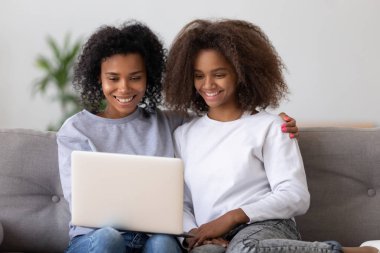 Siyah anne ve kızı seyretmek video üstünde laptop gülümseyen