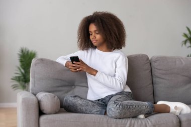 Siyah genç kız smartphone kullanarak kanepede relax