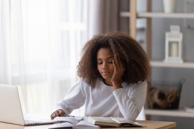 Dreamy black teenager distracted from preparing homework clipart