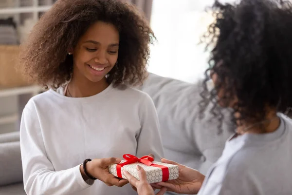 Black mom give birthday present to smiling daughter