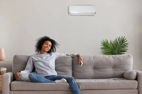 Kalm zwart vrouwelijke ontspannen op de Bank onder air conditioner — Stockfoto