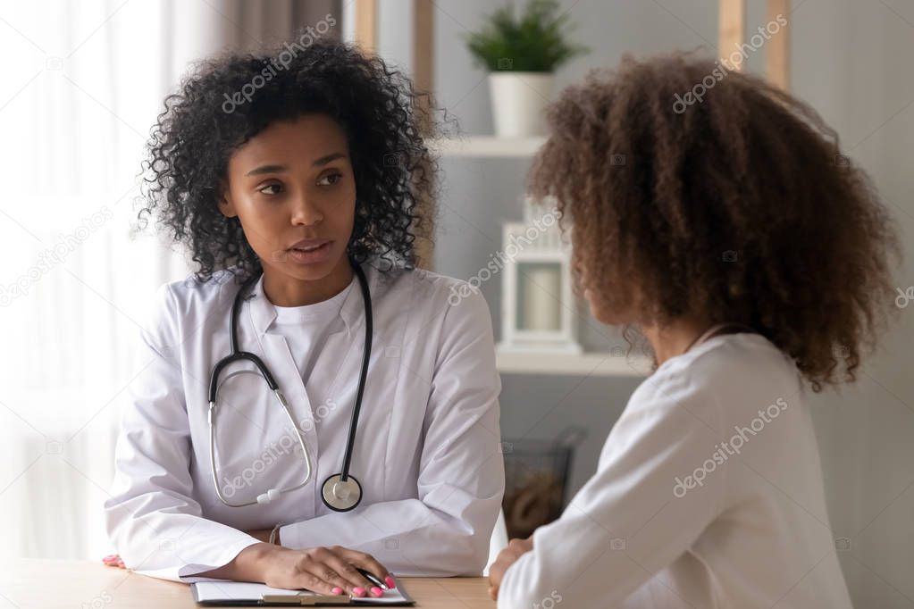 Serious black female doctor consult teenage girl