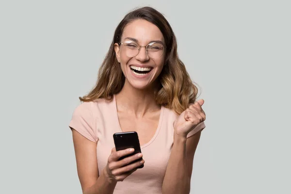 Happy funny millennial woman celebrating mobile win isolated on background — Stock Photo, Image