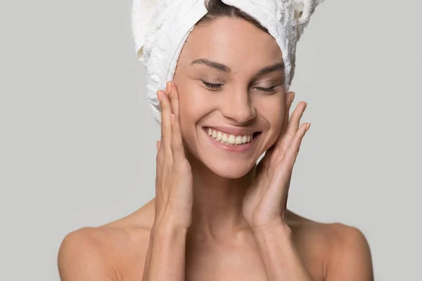 Happy woman with towel on head touching healthy moisturized skin — Stock Photo, Image