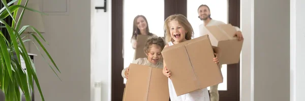 Pareja y niños pequeños con cajas corriendo en casa nueva — Foto de Stock