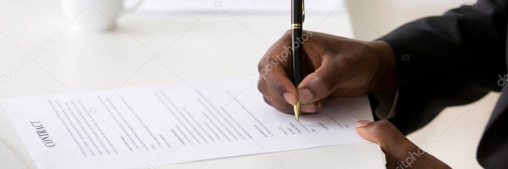 Closeup african businessman hands holds pen affirming contract with signature