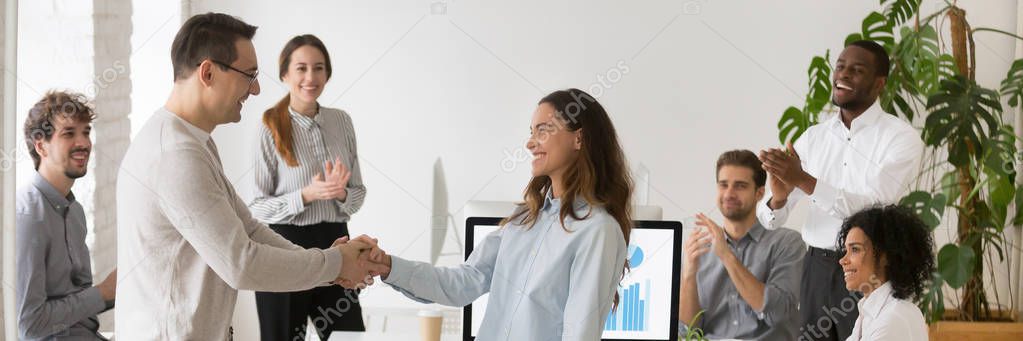 Boss handshaking with mixed race female employee congratulating with success