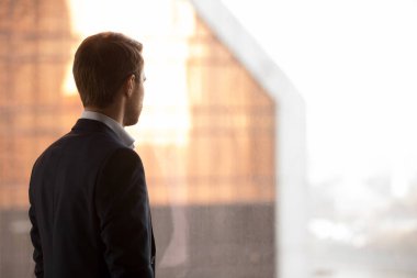 Zengin işadamı geri penceresine bakarak ayakta, arkadan görünüş