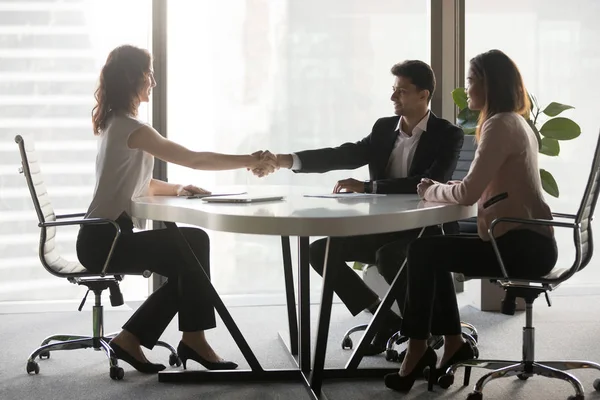 Happy diverse business partners handshaking at office meeting