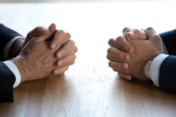 Clasped hands of two businessmen negotiators opponents opposite on table — Stock Photo, Image