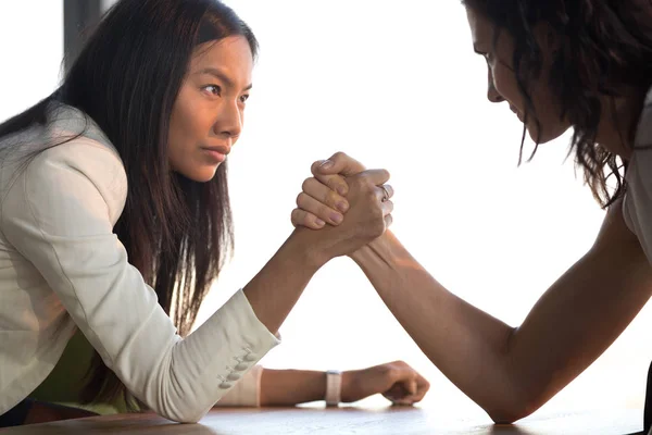 Young asian and caucasian businesswomen armwrestling struggle for leadership — Stock Photo, Image