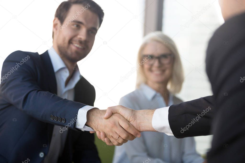 Smiling successful businessmen in suits shaking hands expressing respect