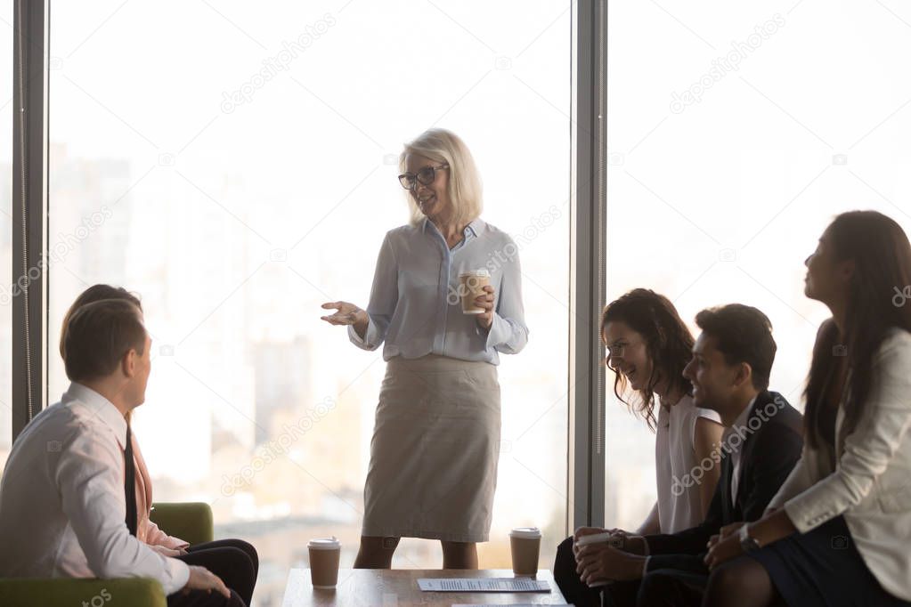 Friendly workers group and middle aged female boss have fun conversation