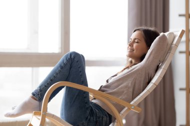 Relaxed calm young woman lounging sitting in comfortable rocking chair clipart