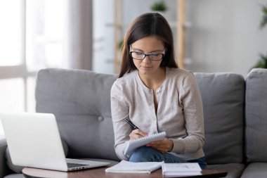 Genç kız öğrenci çalışma evde notları not defterinde yapmak.