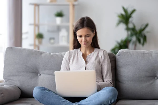 Felice teen ragazza utilizzando il computer portatile navigazione web seduto sul divano — Foto Stock